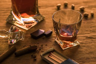 Glass of brandy with cigars, lighter and matches on wooden table clipart