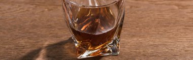 Glass of brandy on wooden table, panoramic shot clipart