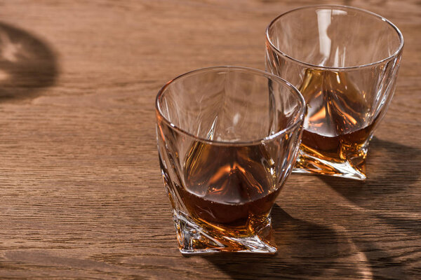 Two glasses of brandy with shadow on wooden table