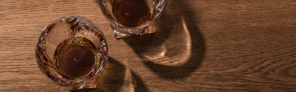 Top view of brandy in glasses on wooden table, panoramic shot
