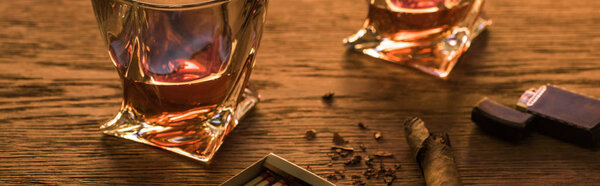 Glasses of brandy with cigar, lighter and matches on wooden table, panoramic shot