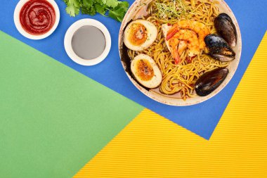 Baharatlı deniz mahsulleri ramen 'i kırmızı biber yanında ve soya sosu çok renkli yüzeyde.