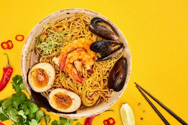 Top view of seafood ramen near fresh ingredients and chopsticks on yellow surface — Stock Image Top View Seafood Ramen Fresh Ingredients Chopsticks Yellow Surface Royalty Free Stock Images