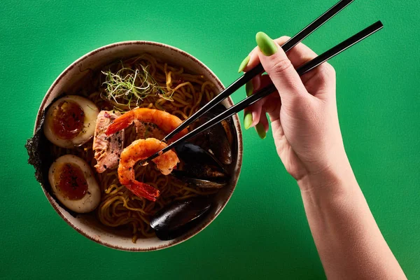 Cropped view of woman eating spicy seafood ramen with chopsticks on green surface — Stock Image Cropped View Woman Eating Spicy Seafood Ramen Chopsticks Green Surface Stock Photo