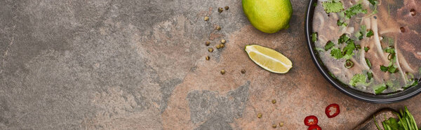 top view of pho in bowl near lime, chili on stone background, panoramic shot