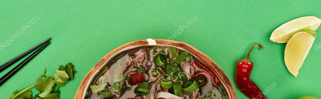 Top view of pho in bowl near chopsticks, lime, chili and coriander on green background, panoramic shot — Stock Image Top View Pho Bowl Chopsticks Lime Chili Coriander Green Background Royalty Free Stock Images