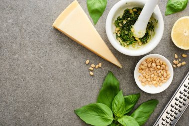 Pesto sosunun en üst görüntüsü ham malzemeler ve gri yüzeyde pişirme aletleri