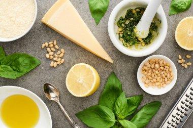 Pesto sosunun en üst görüntüsü ham malzemeler ve gri yüzeyde pişirme aletleri