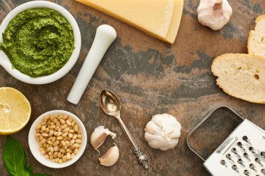 Pesto sosunun üst görüntüsü, malzemeler ve ekmek taş yüzeyde.