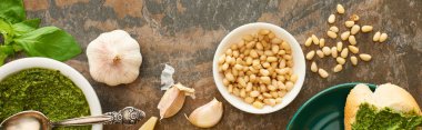 Pesto soslu baget diliminin üst görüntüsü taş yüzeyindeki taze malzemelerin yanında, panoramik çekim.