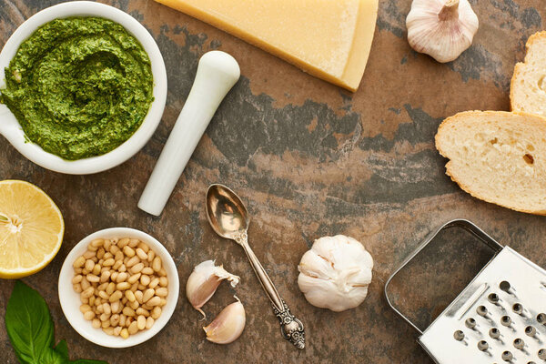 top view of pesto sauce, ingredients and bread on stone surface