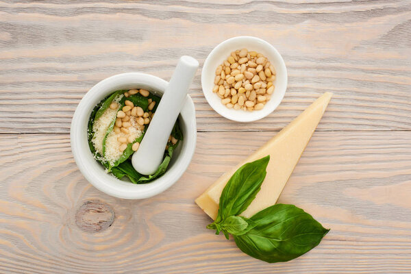 top view of pesto sauce raw ingredients in pounder on wooden table