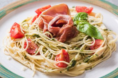 Domates, fesleğen ve prosciutto ile pişmiş Pappardelle 'in yakın görüntüsü