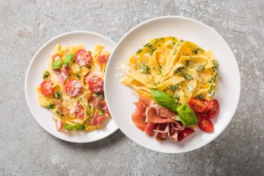 Domatesli, fesleğenli ve gri tabaklarda jambonlu Pappardelle 'in seçici odak noktası