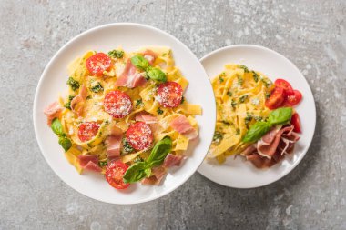 Domatesli, fesleğenli ve gri tabaklarda jambonlu Pappardelle 'in seçici odak noktası