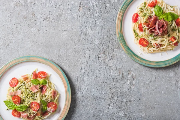 Ovanifrån Pappardelle Med Tomater Basilika Och Prosciutto Plattor Grå Yta — Stockfoto