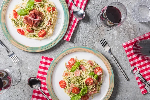 Bovenaanzicht Van Pappardelle Met Tomaten Basilicum Prosciutto Borden Geruite Servetten — Stockfoto