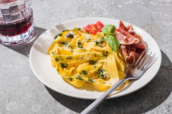Tasty Pappardelle Tomatoes Pesto Prosciutto Fork Red Wine Grey Surface — Stock Photo, Image