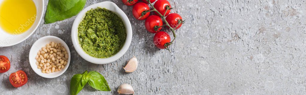 Top view of raw tomatoes, garlic, basil, pine nuts, olive oil, pesto sauce on grey surface, panoramic shot — Stock Image Top View Raw Tomatoes Garlic Basil Pine Nuts Olive Oil Stock Picture