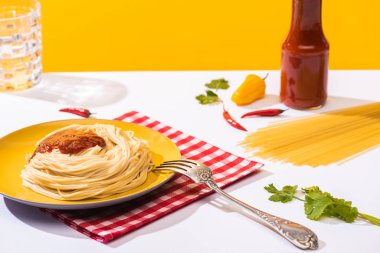 Beyaz arka planda ketçaplı ev yapımı spagetti, kişniş ve biberli spagetti.