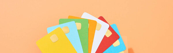 вид сверху на многоцветные пустые кредитные карты на фоне персика, панорамный снимок
