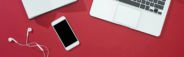 スマートフォン ノートパソコン イヤフォン ノートパソコンの上からの赤の背景 パノラマ写真 — ストック写真