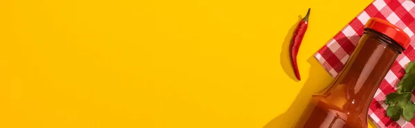 黄色の背景にチリソース コリアンダー 唐辛子とボトルのトップビュー パノラマショット — ストック写真