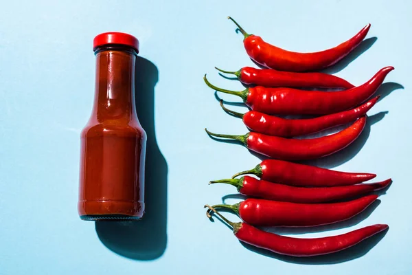 Draufsicht Auf Chilisoße Und Reife Chilischoten Auf Blauer Oberfläche — Stockfoto