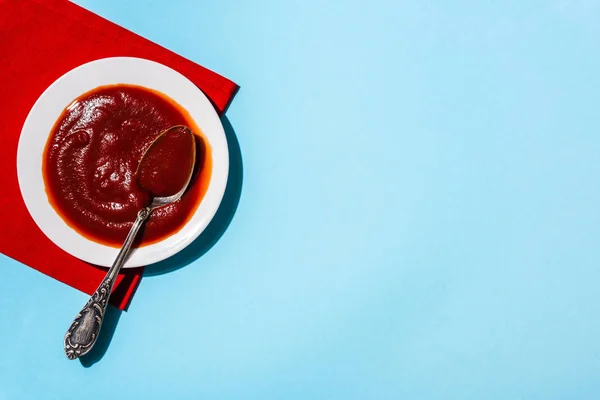 Κάτοψη Νόστιμης Σάλτσας Ντομάτας Πιάτο Κουτάλι Κόκκινη Πετσέτα Μπλε Επιφάνεια — Φωτογραφία Αρχείου