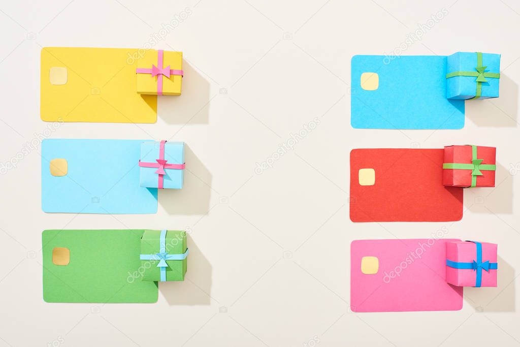 top view of multicolored empty credit cards and gift boxes on white background