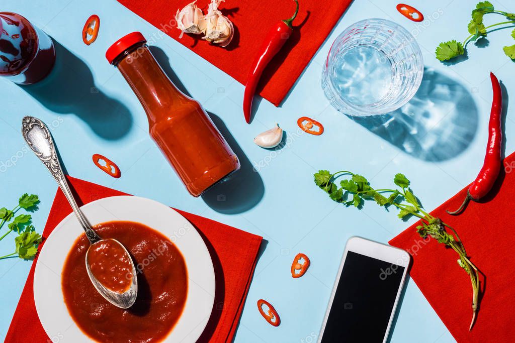 Vista superior de ketchup casero con ajo y chiles junto a smartphone
