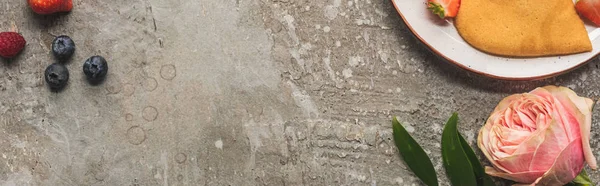 バラの近くの灰色のコンクリートの表面に果実のあるハート型のパンケーキの上からの眺めパノラマショット — ストック写真