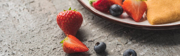 close up view of fresh berries near delicious heart shaped pancakes on grey concrete surface, panoramic shot