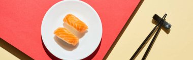 Kırmızı ve bej yüzey üzerinde çubuk somonlu taze nigiri manzarası, panoramik çekim