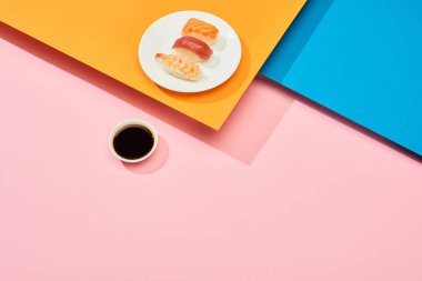 Soya sosu yanında somon, ton balığı ve karides ile taze nigiri. Mavi, pembe, turuncu yüzey.