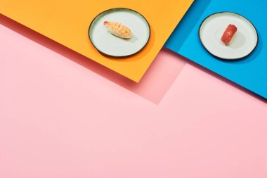 Ton balıklı taze nigiri ve mavi, pembe, turuncu yüzey üzerine karides.