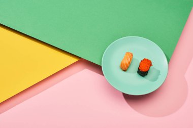 Somon balıklı taze nigiri ve sarı, pembe, yeşil arka planda kırmızı havyar.