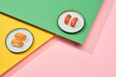 Somon balıklı taze nigiri ve sarı, pembe, yeşil arka planda ton balığı.