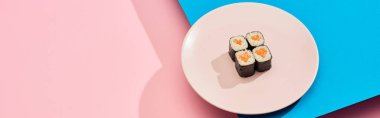 fresh maki with salmon on blue, pink background, panoramic shot clipart