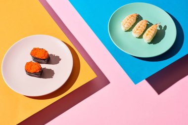 Karidesli taze nigiri ve mavi, pembe, turuncu arka planda kırmızı havyar.