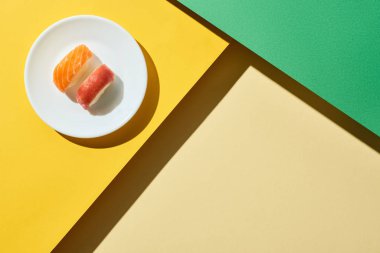 top view of fresh nigiri with salmon and tuna on green and yellow surface clipart