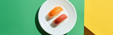 top view of fresh nigiri with salmon and tuna on green and yellow surface, panoramic shot clipart