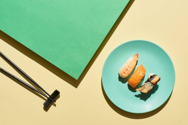 Somon, karides ve yılan balığıyla yeşil ve sarı yüzeye yakın taze nigiri manzarası.