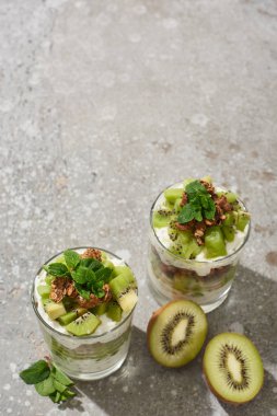 Gri beton yüzeyde kivi ve yoğurtlu taze granola.