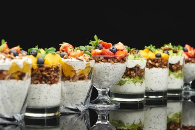 Taze meyve ve böğürtlenlerle siyah üzerine izole edilmiş taze granola seçici odağı