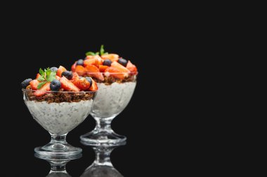 Böğürtlen ve chia tohumlarıyla siyah üzerine izole edilmiş taze granola seçici odağı