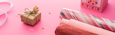 Sevgililer günü konfetisi, ambalaj kağıdı, pembe arka planda hediye kutusu, panoramik çekim