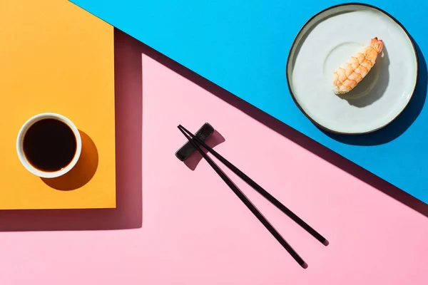 在酱油旁边放着虾仁 在蓝色 橙色背景上放着筷子的新鲜黑鬼的头像 — 图库照片
