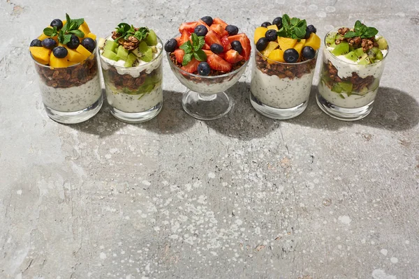 灰色のコンクリートの表面に果物や果実のあるガラスのおいしいグラノーラ — ストック写真