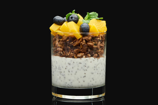 fresh granola with canned peach, blueberries and chia seeds isolated on black